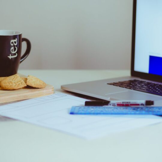 cup of tea and cookies on a table next to a computer