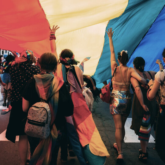 People walking on a street under a rainbow flag