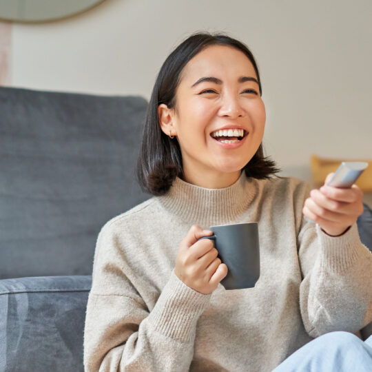 woman watching CTV with coffee cup and remote