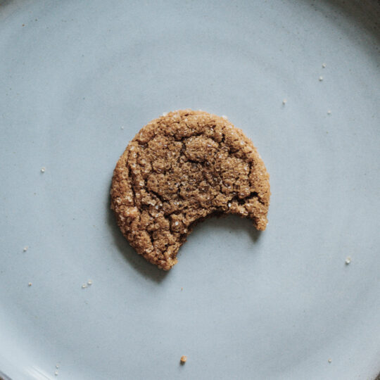 Photo d'un cookie entamé placé dans une assiette grise posée sur une table blanche