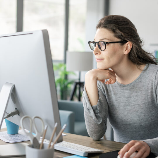 Femme assise derrière un bureau et regardant un écran d'ordinateur