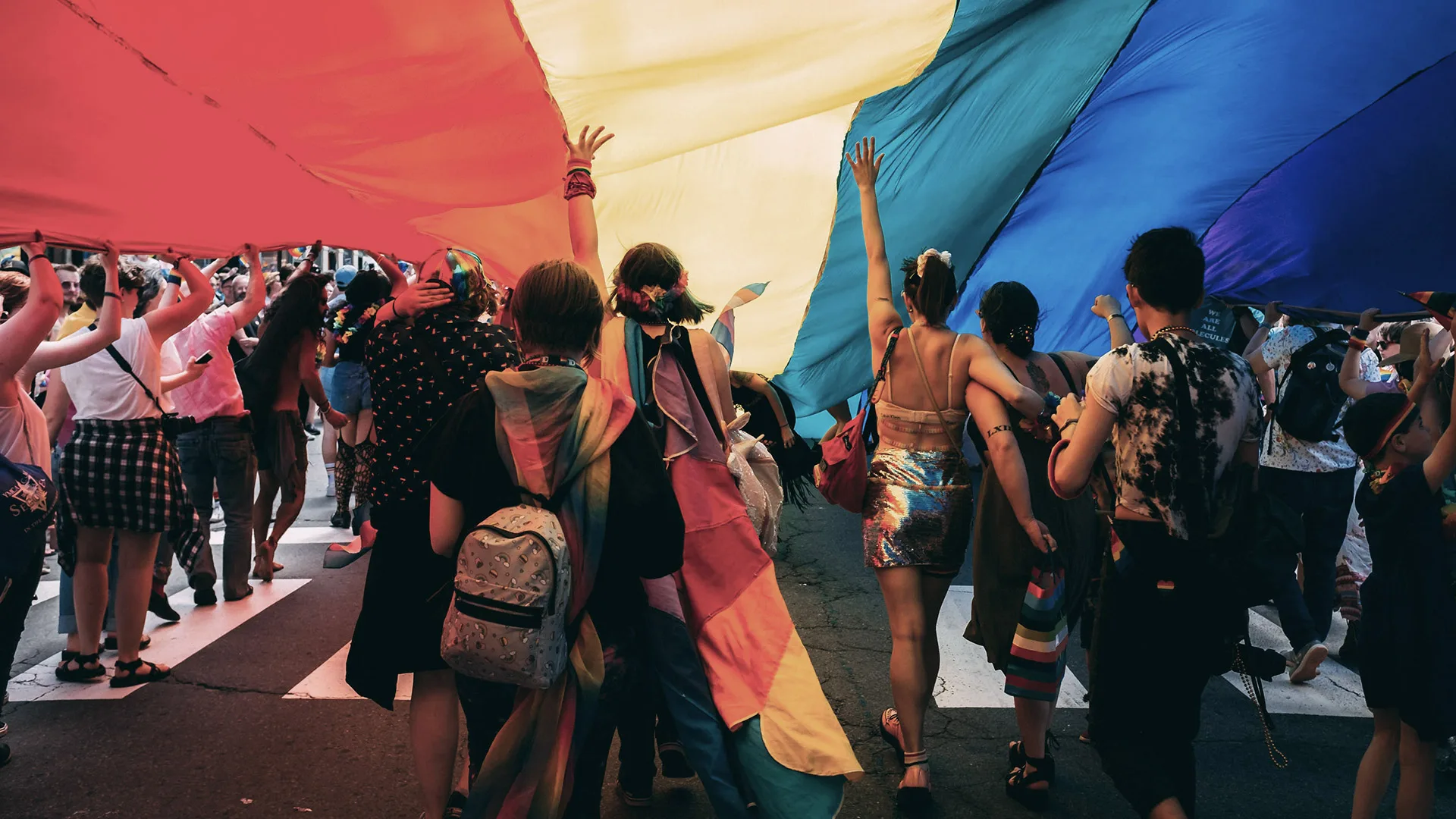 People under a rainbow flag to show Pride at Index