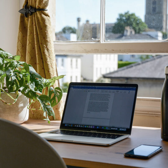 laptop on a desk by a window