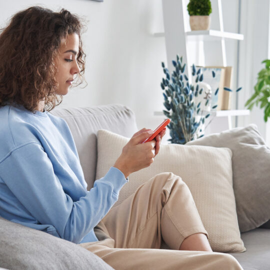 person sitting on a couch on their mobile phone representing mobile ad market